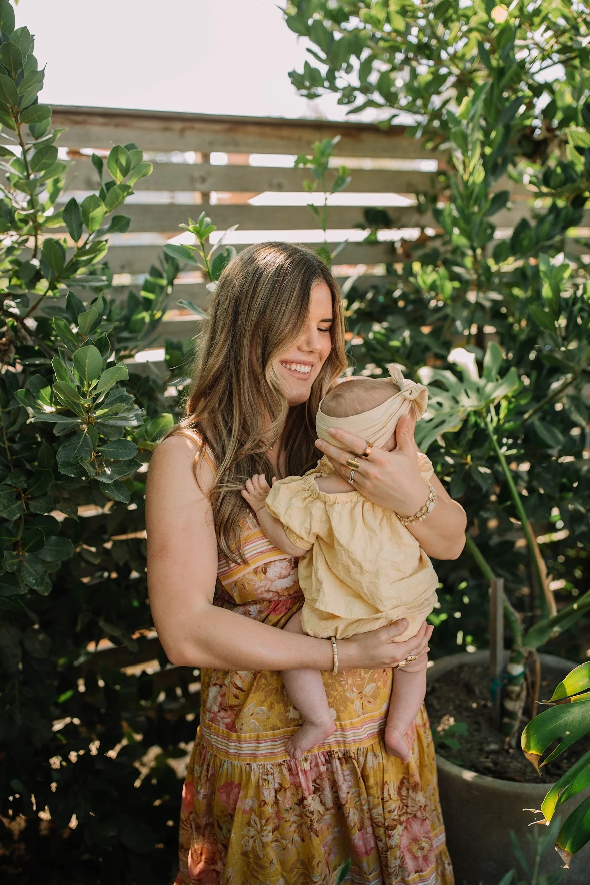 Cambria holding her baby in a sunlit garden