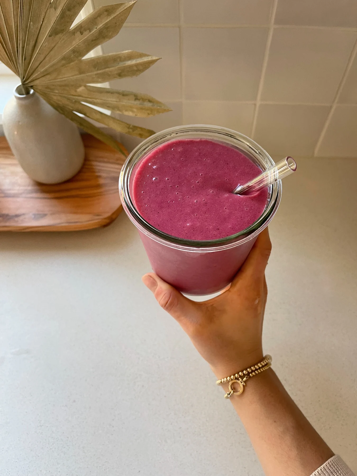 A pink smoothie with flowers beside it
